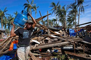 A typhoon victim carries a gas tank for cooking past a house destroyed by Typhoon Hagupit in Borongan city, Samar Photo: ERIK DE CASTRO/REUTERS